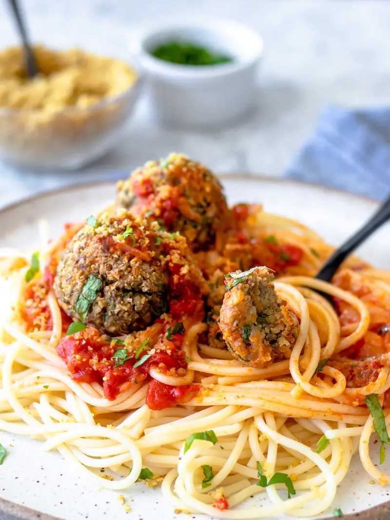 almôndegas de lentilha veganas servidas com macarrão espaguete, molho vermelho e parmesão vegano