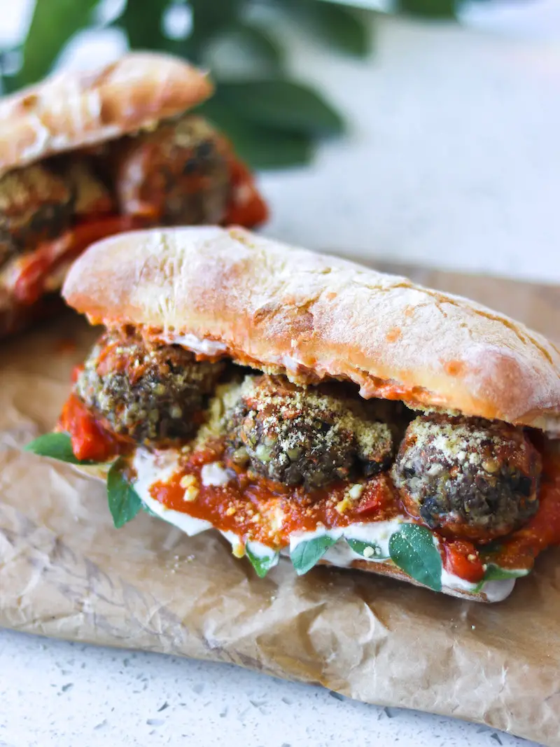 almôndegas de lentilha veganas servidas no pão com molho vermelho, maionese de tofu e manjericão