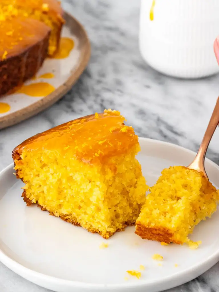 vista lateral de um pedaço de bolo de laranja com calda cortado com um garfo