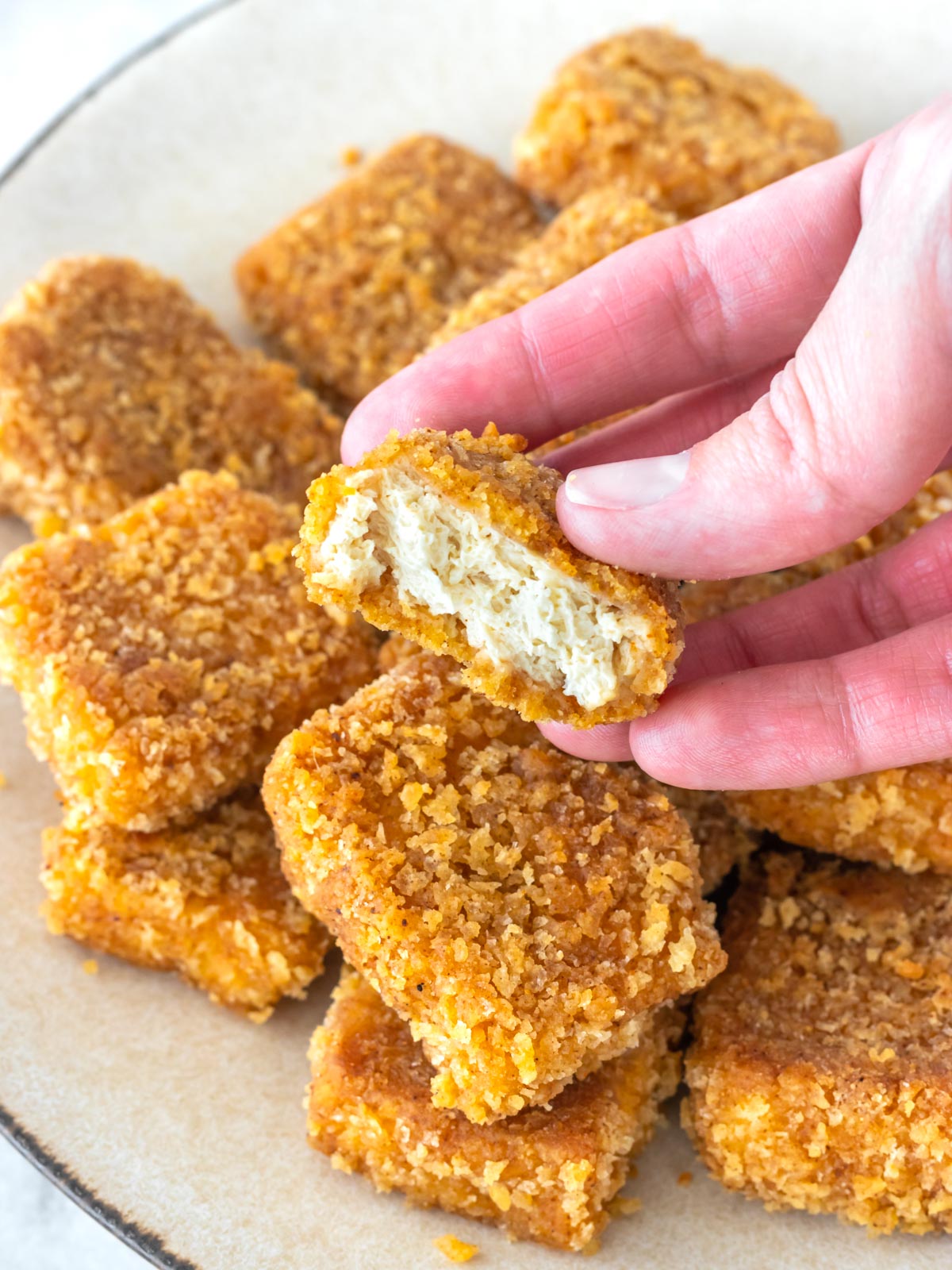 mão segurando um nuggets vegano mordido