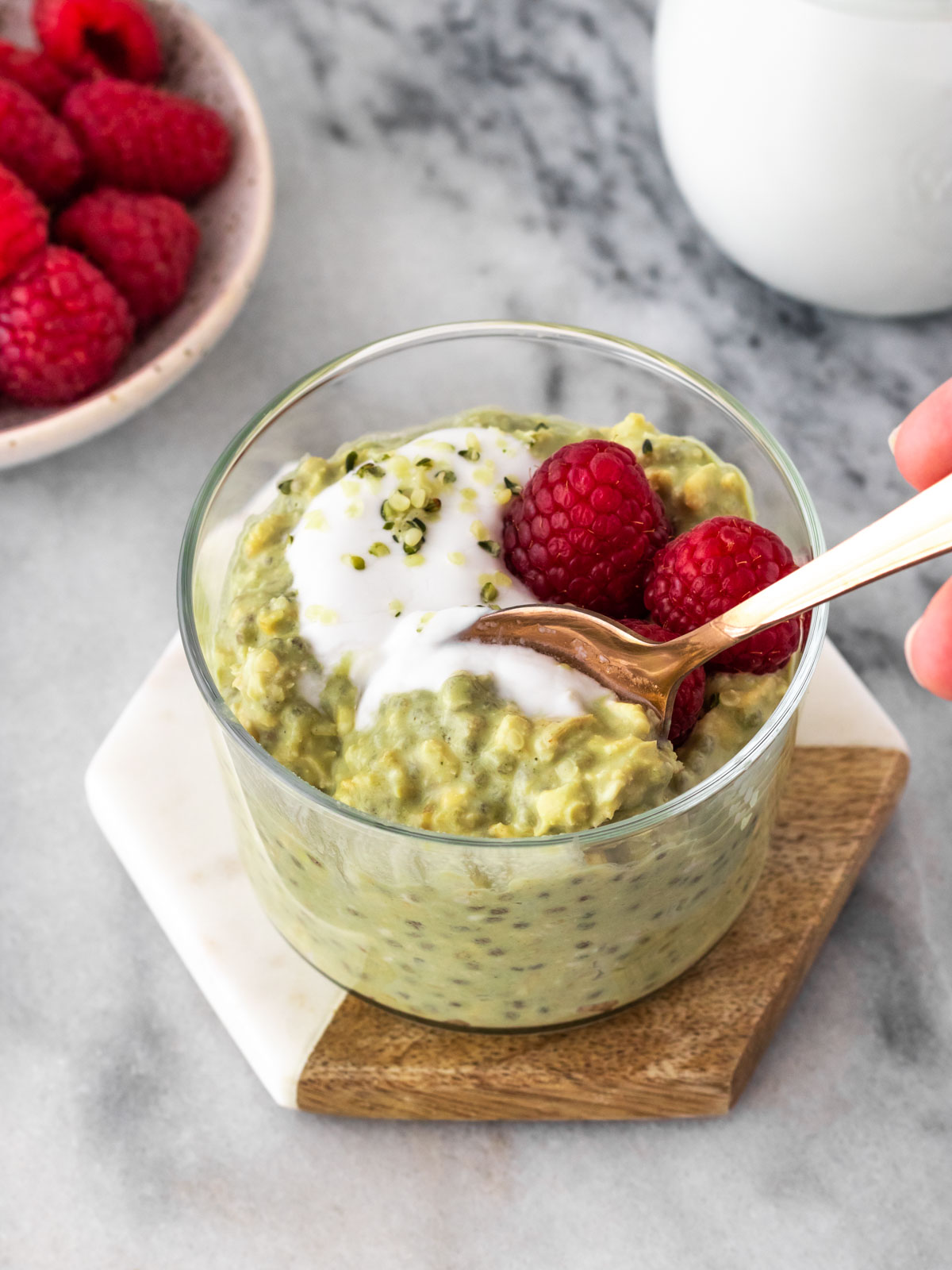 overnight oats de matcha servido em um copinho com iogurte, sementes e framboesa