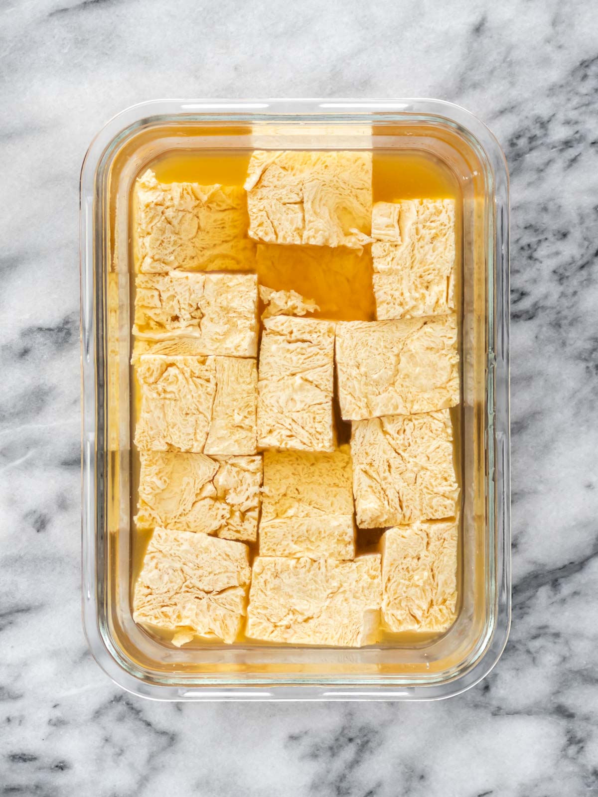 pedaços de tofu marinando no caldo de legumes dentro de um pote