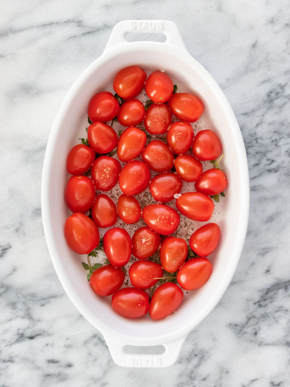 tomates-cereja em uma assadeira com tomilho fresco, sal e pimenta-do-reino