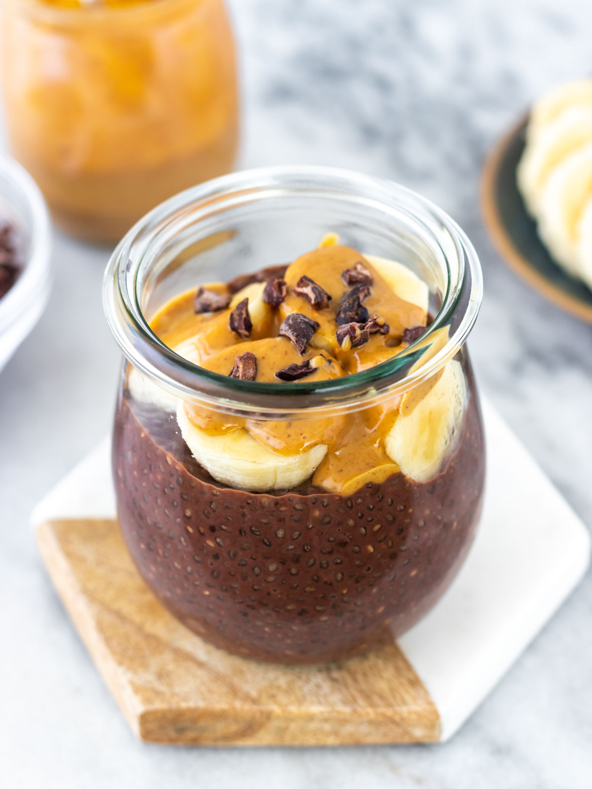 pudim de chia de chocolate servido com banana, pasta de amendoim e nibs de cacau