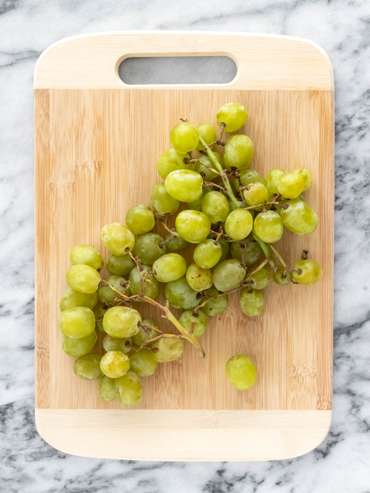 cacho de uvas em cima de uma tábua de bambu