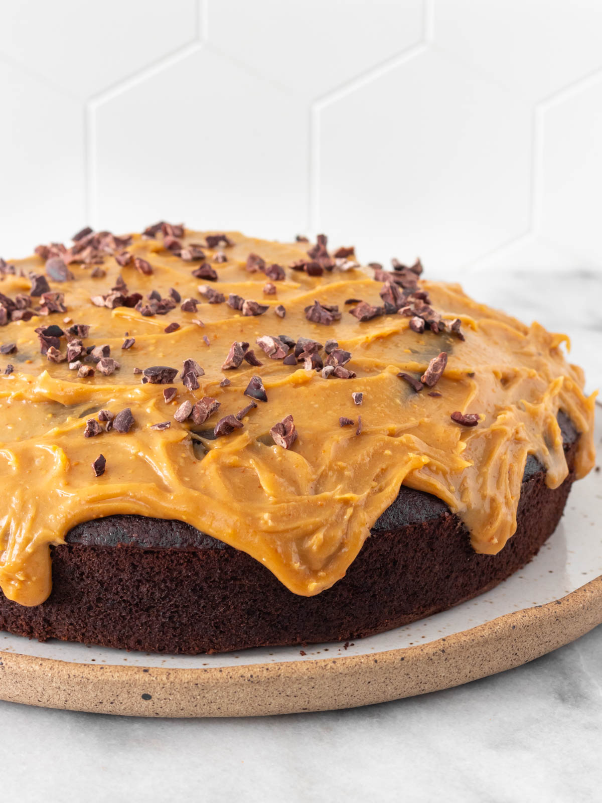 Bolo de chocolate com cobertura de amendoim e nibs de cacau.