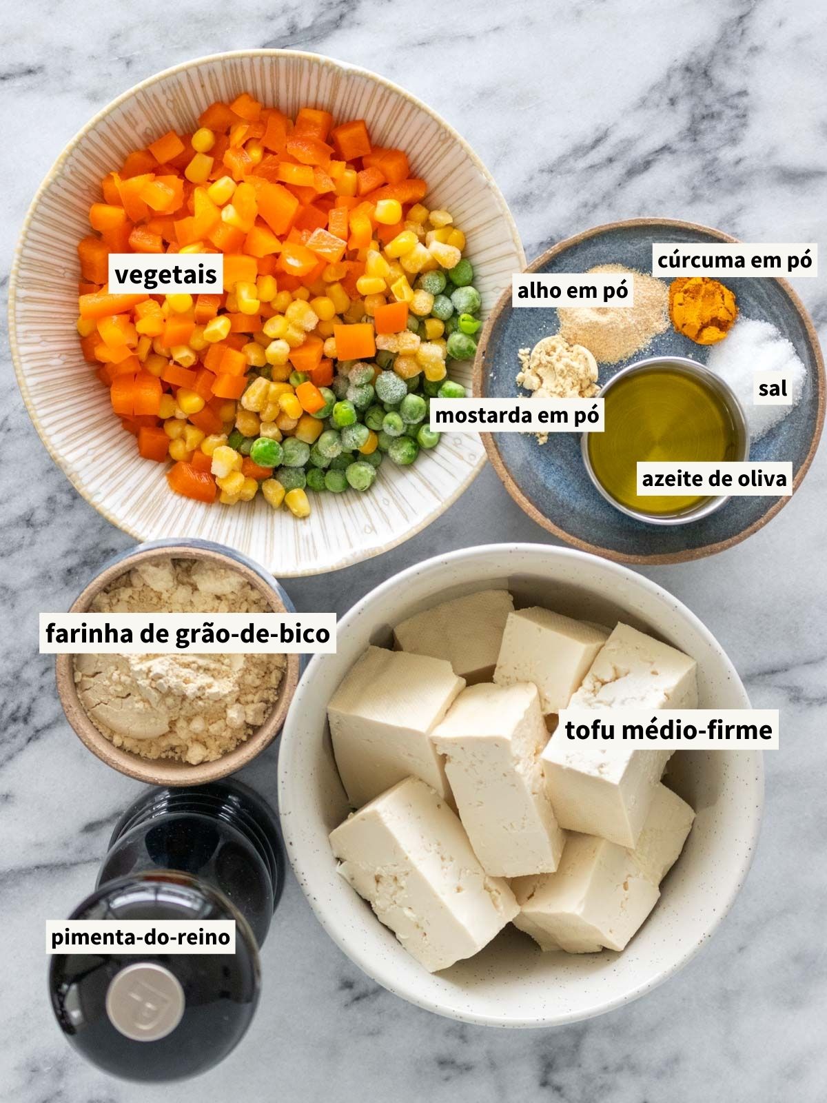 ingredientes para fazer muffin de legumes, incluindo tofu médio-firme, farinha de grão-de-bico, azeite de oliva, temperos e legumes variados (milho, ervilha e pimentão laranja picado)