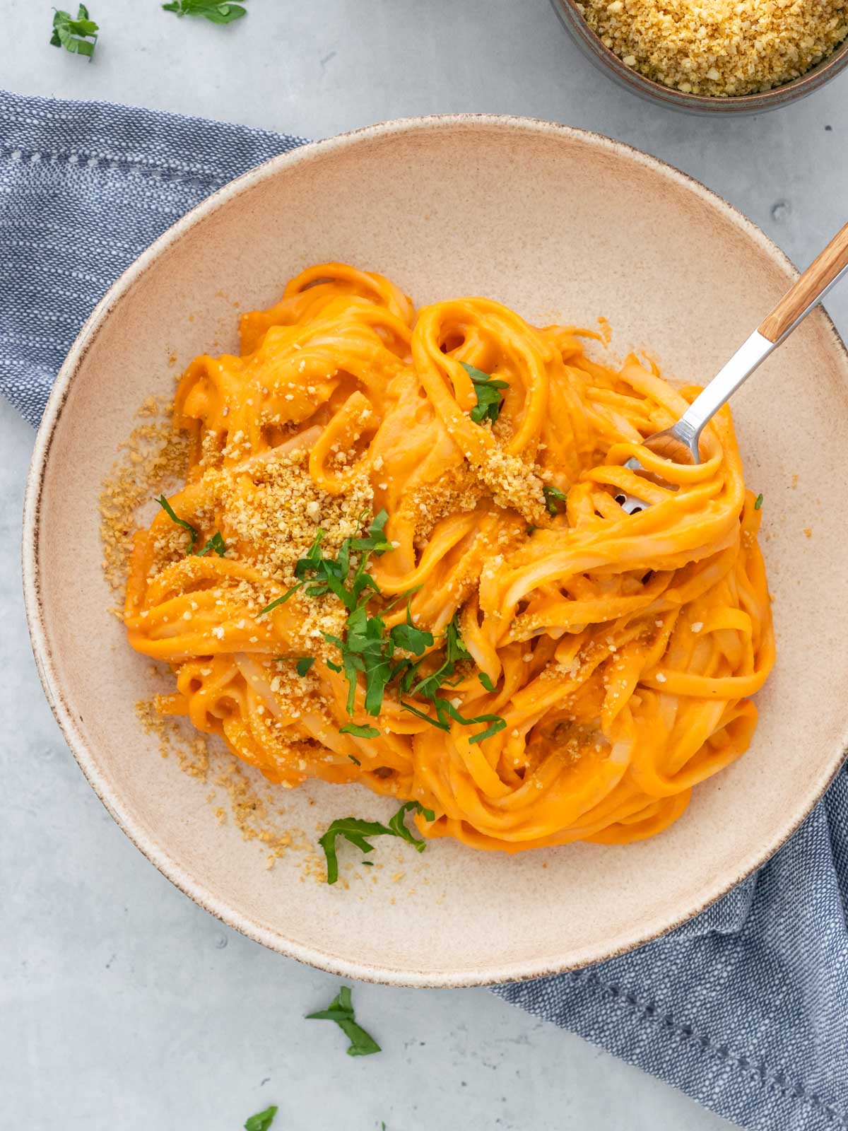 prato de macarrão envolvido com molho de pimentão vermelho assado, servido com parmesão vegano de castanhas e salsinha fresca picada