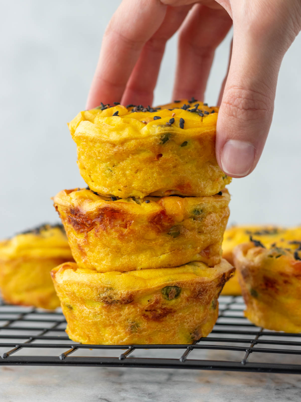 mão pegando um muffin de legumes de uma pilha com três muffins