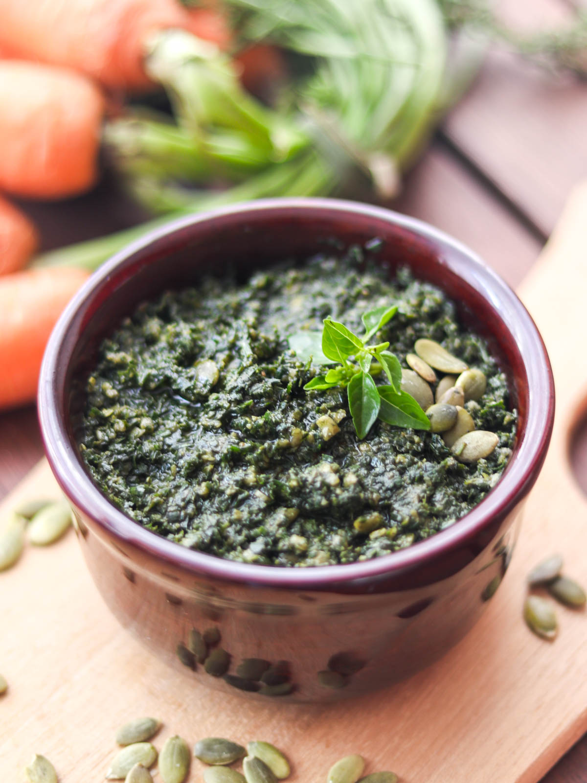 molho pesto servido em um pote, regado com azeite de oliva e enfeitado com folhas de manjericão fresco e sementes de abóbora sem casca