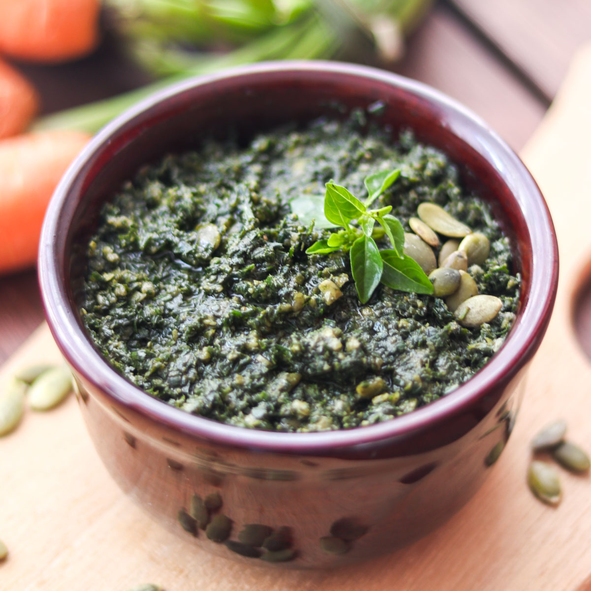 molho pesto servido em um pote, regado com azeite de oliva e enfeitado com folhas de manjericão fresco e sementes de abóbora sem casca