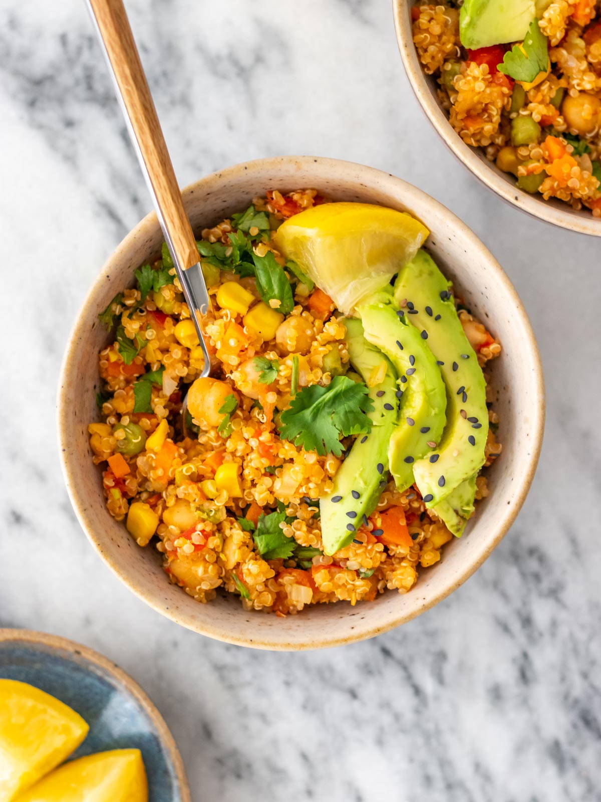 mexido de quinoa com legumes e grão-de-bico servido com fatias de abacate e sementes de gergelim