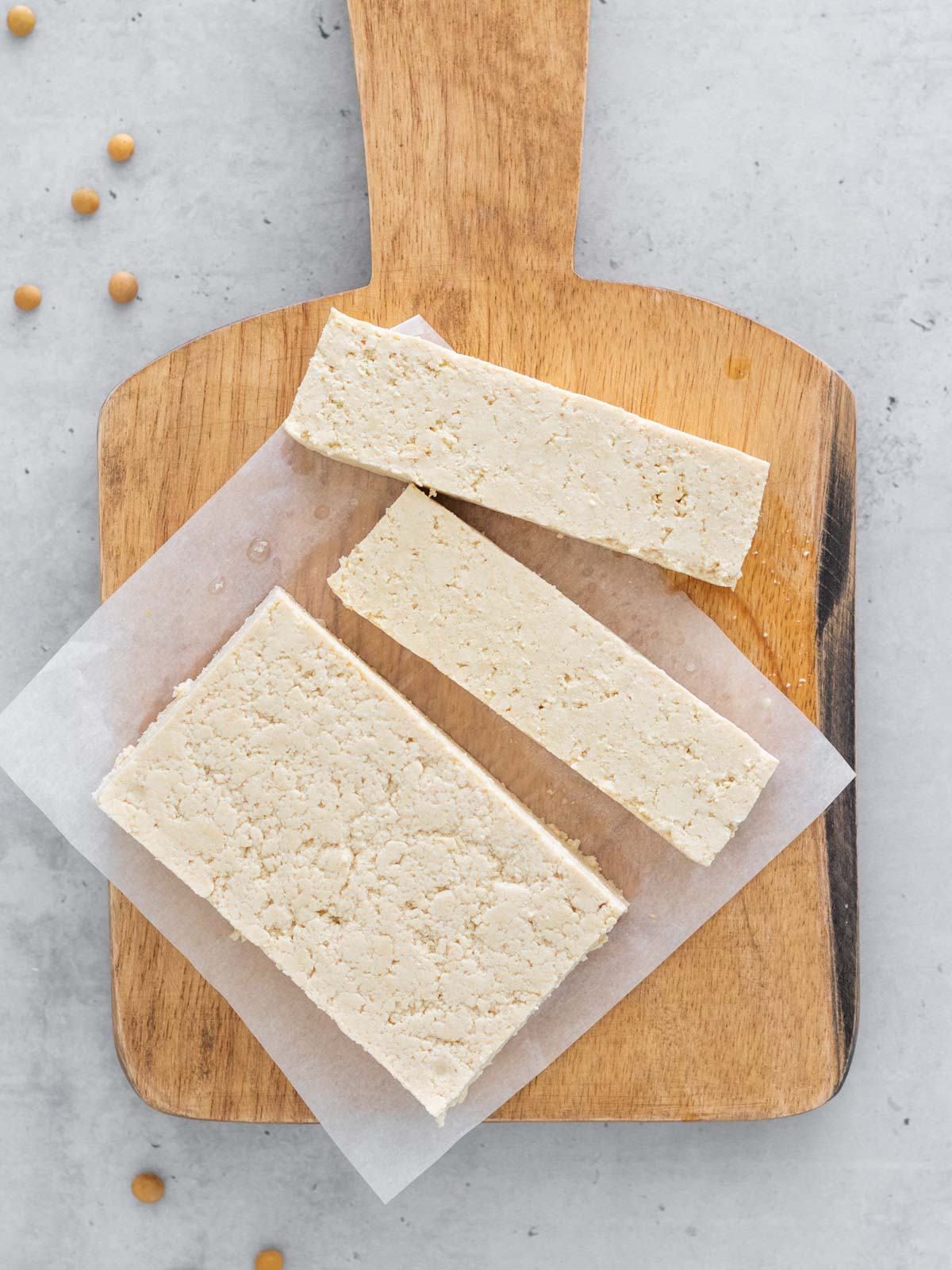 bloco de tofu caseiro cortado em cima de uma tábua, mostrando sua textura firme