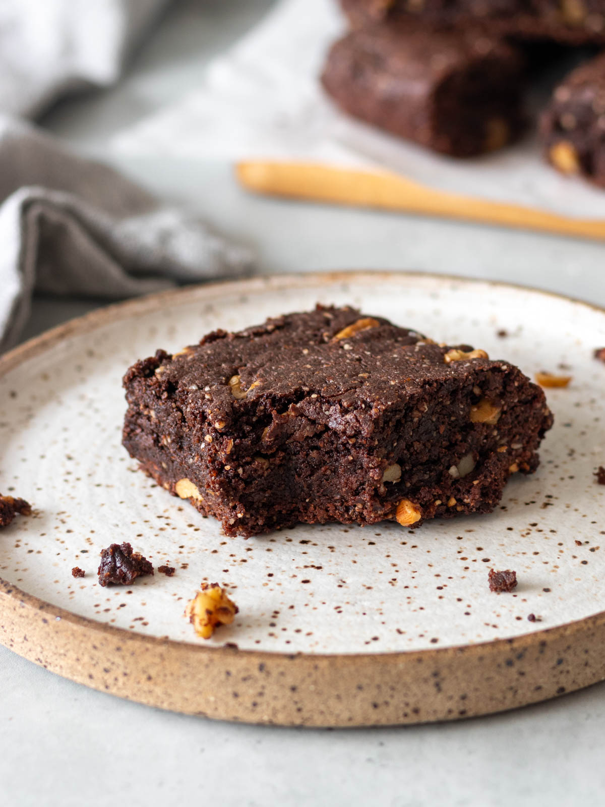 pedaço de brownie de amêndoas mordido em cima de um prato, mostrando seu interior úmido com pedaços de nozes