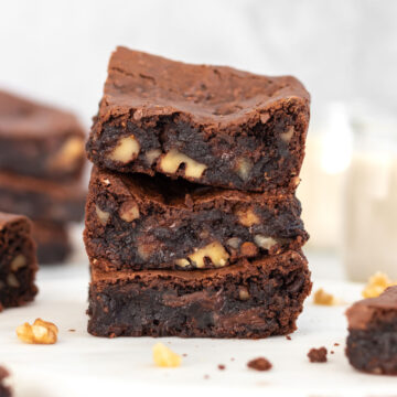 3 fatias de brownie de feijão empilhadas, mostrando seu interior dentro e molhado, com pedaços de nozes picadas e chocolate derretido